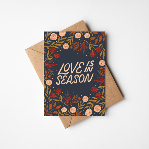 Greeting card with lettering that says love is in season surrounded by flowers